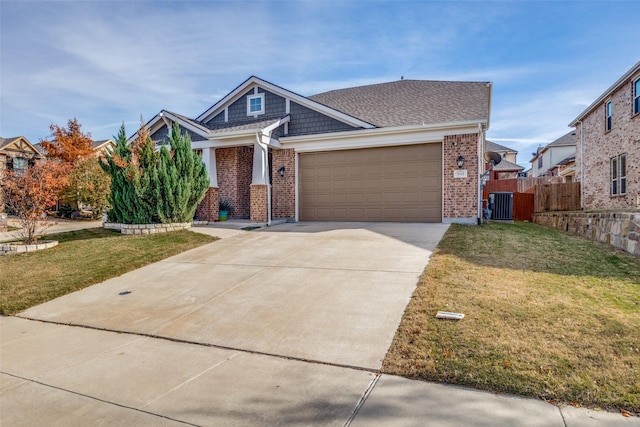 craftsman house with driveway, a front lawn, brick siding, central AC, and a garage