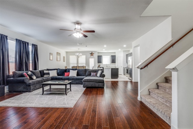 living area with ceiling fan with notable chandelier, hardwood / wood-style floors, a wealth of natural light, and stairs