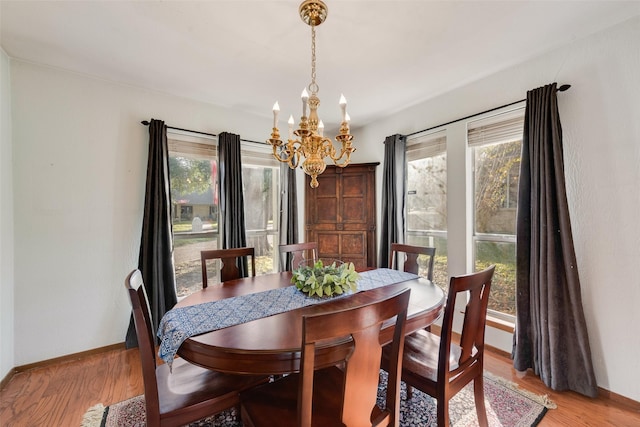 dining area with hardwood / wood-style floors, a healthy amount of sunlight, and a notable chandelier