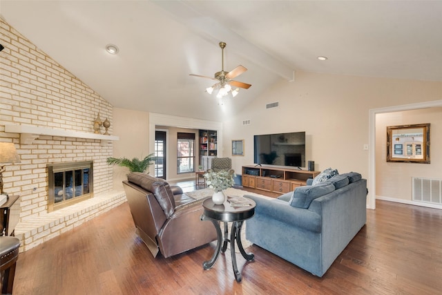 living room with vaulted ceiling with beams, ceiling fan, dark hardwood / wood-style flooring, and a brick fireplace