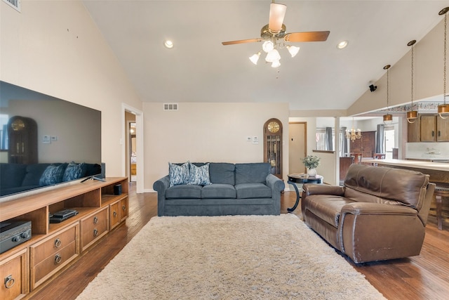 living room featuring dark hardwood / wood-style flooring, high vaulted ceiling, and ceiling fan with notable chandelier