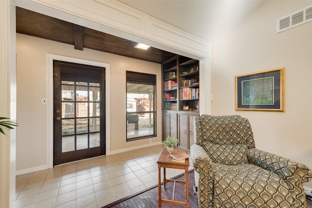 living area with tile patterned floors, beam ceiling, and built in features