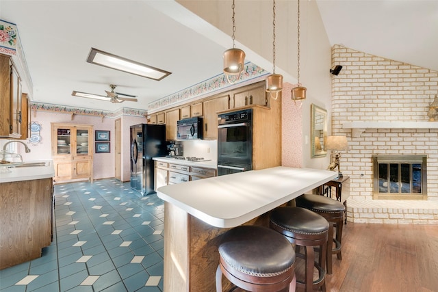 kitchen with kitchen peninsula, a kitchen breakfast bar, vaulted ceiling, black appliances, and hanging light fixtures