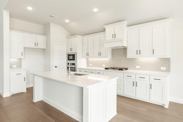 kitchen featuring stainless steel gas cooktop, white cabinets, a sink, an island with sink, and built in microwave