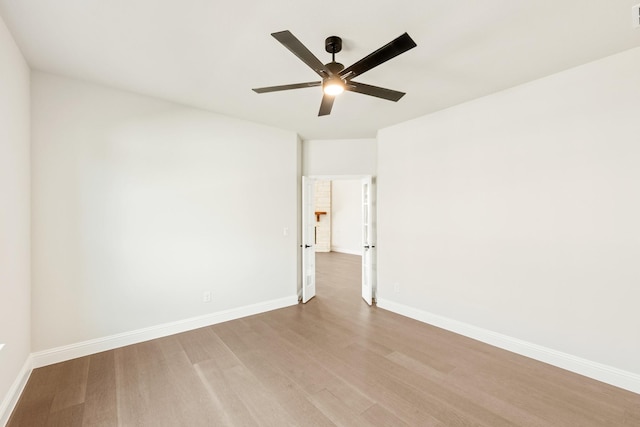 empty room featuring ceiling fan, wood finished floors, visible vents, and baseboards