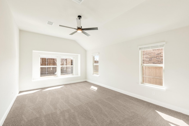 carpeted empty room featuring lofted ceiling, visible vents, ceiling fan, and baseboards