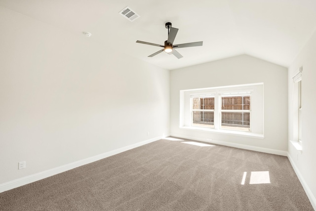 carpeted empty room with vaulted ceiling, a ceiling fan, visible vents, and baseboards