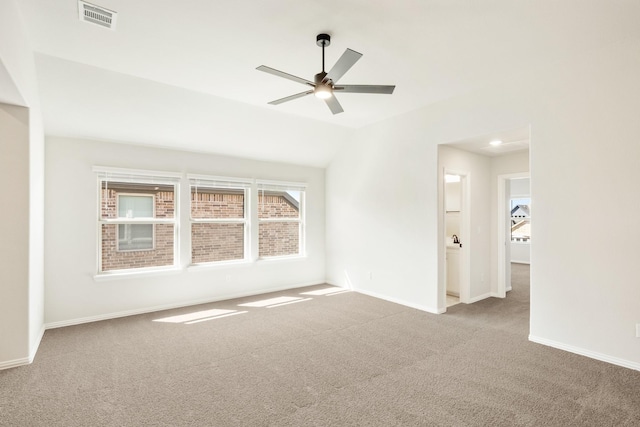 carpeted empty room featuring lofted ceiling, baseboards, visible vents, and ceiling fan