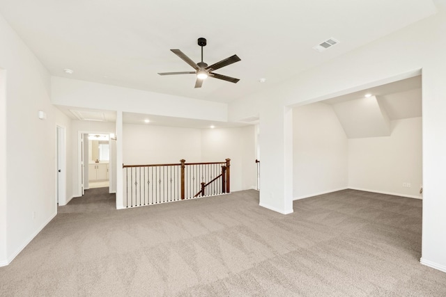 carpeted spare room featuring attic access, visible vents, ceiling fan, and baseboards