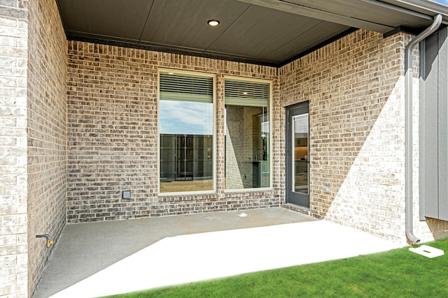 entrance to property featuring a patio and brick siding