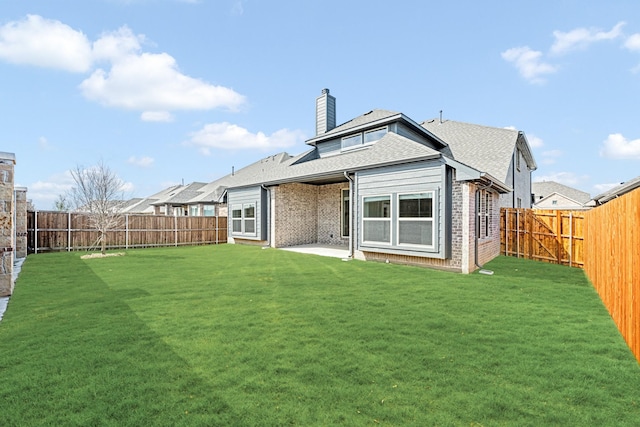 rear view of property featuring brick siding, a yard, a chimney, and a fenced backyard