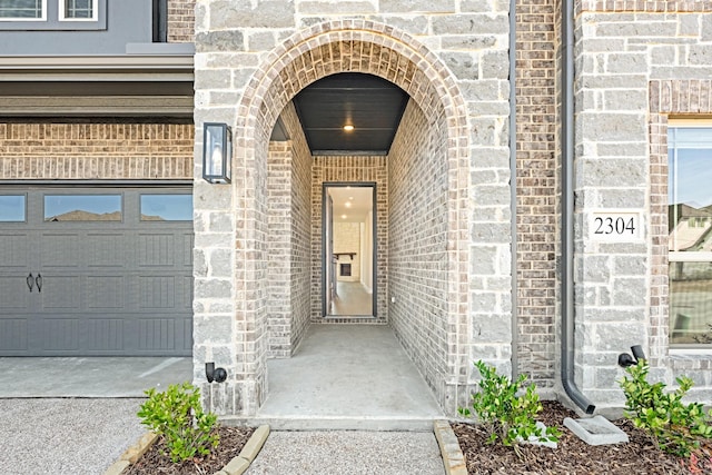 doorway to property featuring a garage, stone siding, and brick siding