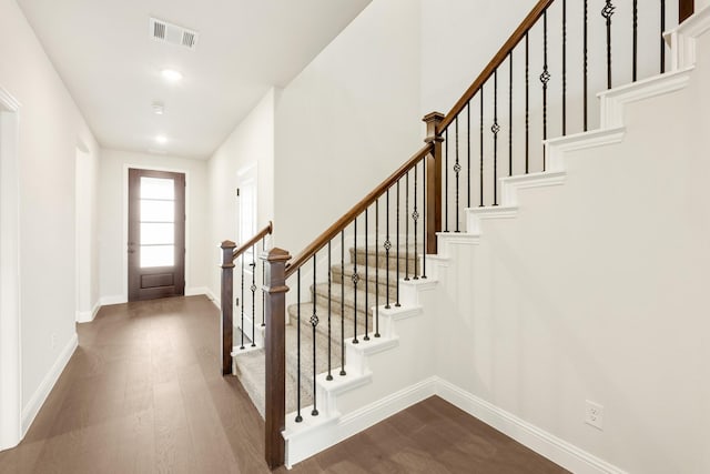 entryway with dark wood-style floors, stairs, visible vents, and baseboards