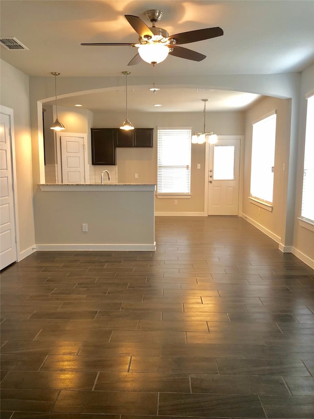 unfurnished living room with dark hardwood / wood-style flooring and ceiling fan with notable chandelier