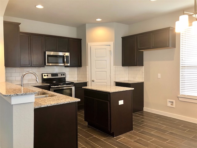 kitchen with a healthy amount of sunlight, a kitchen island, light stone countertops, and stainless steel appliances