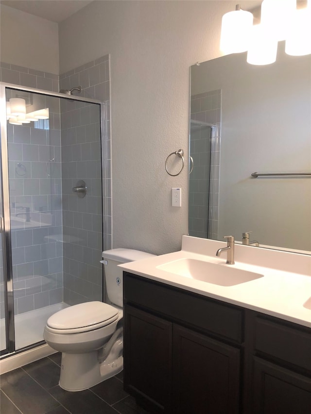 bathroom with tile patterned flooring, vanity, toilet, and an enclosed shower