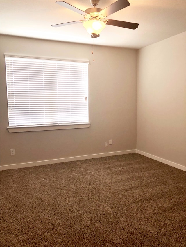 empty room with ceiling fan and dark colored carpet