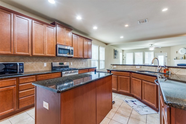 kitchen featuring dark stone counters, sink, ceiling fan, appliances with stainless steel finishes, and a kitchen island