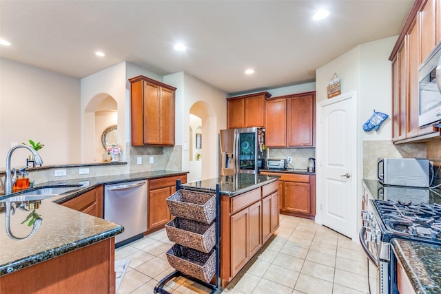 kitchen with dark stone counters, sink, a kitchen island, and stainless steel appliances