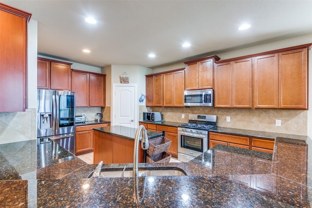 kitchen with dark stone countertops, decorative backsplash, sink, and appliances with stainless steel finishes