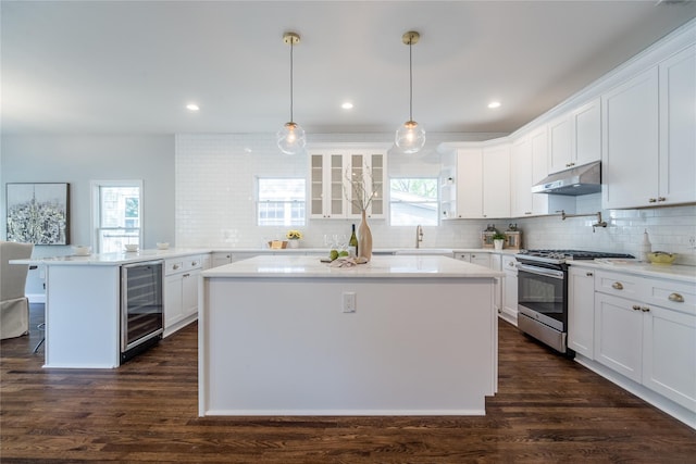 kitchen with gas range, white cabinetry, dark wood-type flooring, and beverage cooler