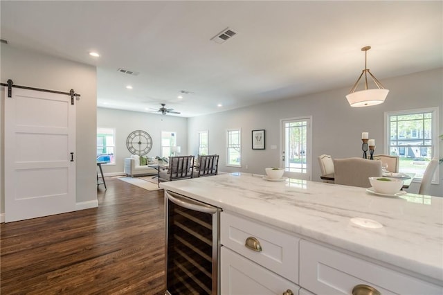 kitchen with dark hardwood / wood-style flooring, light stone counters, pendant lighting, a barn door, and wine cooler