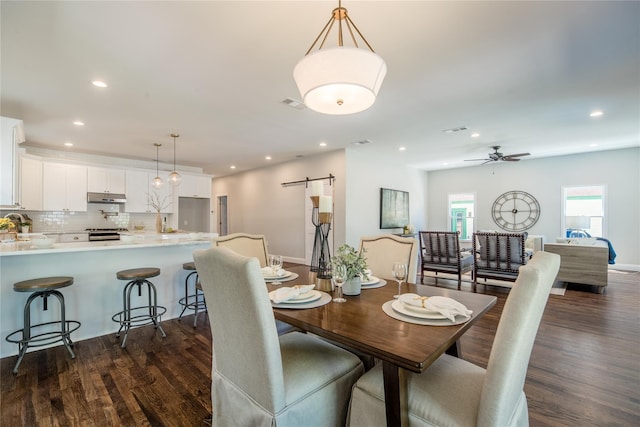 dining area with dark hardwood / wood-style flooring, a barn door, and ceiling fan