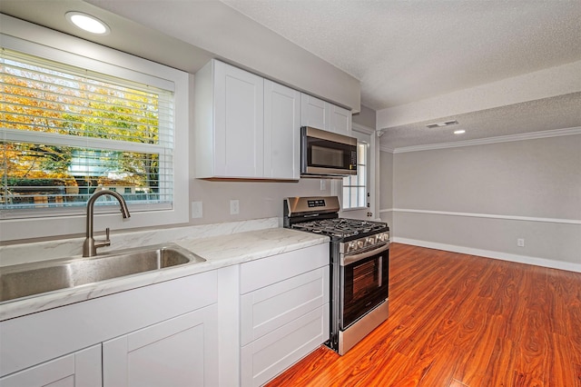 kitchen with appliances with stainless steel finishes, light hardwood / wood-style floors, a healthy amount of sunlight, and sink