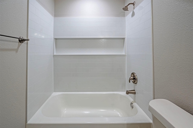 bathroom featuring toilet and tiled shower / bath