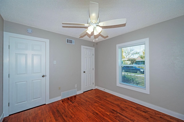 unfurnished bedroom with hardwood / wood-style flooring, ceiling fan, and a textured ceiling