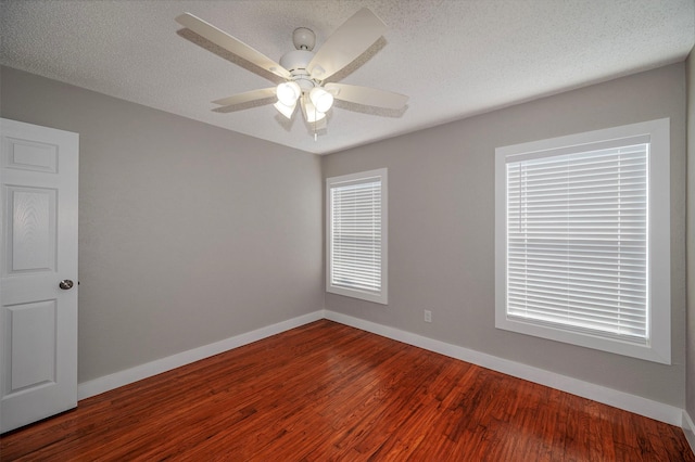 empty room with ceiling fan, wood-type flooring, and a textured ceiling