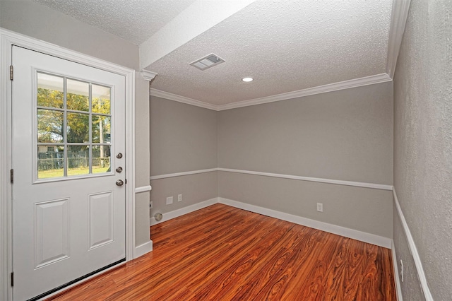 entryway featuring hardwood / wood-style flooring, ornamental molding, and a textured ceiling