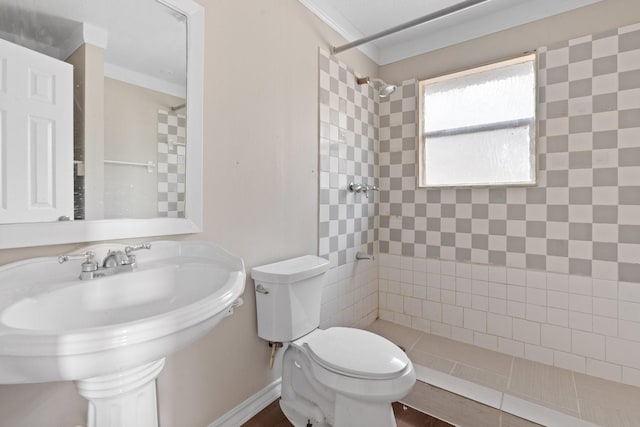 bathroom with crown molding, toilet, sink, and a tile shower