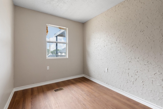 unfurnished room with wood-type flooring and a textured ceiling