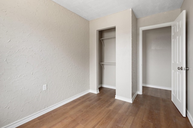 unfurnished bedroom with dark hardwood / wood-style flooring and a closet