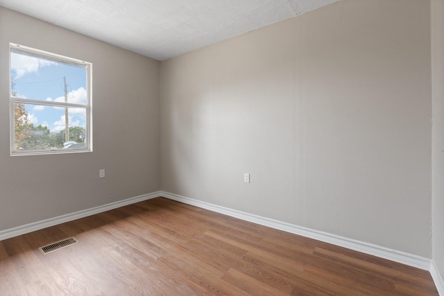 spare room with a textured ceiling and light wood-type flooring