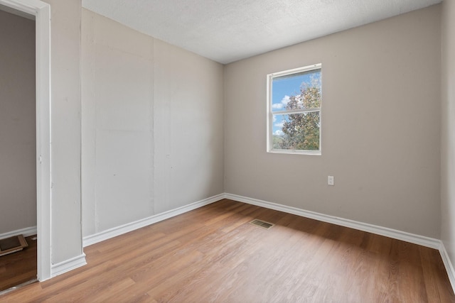 empty room featuring a textured ceiling and light wood-type flooring