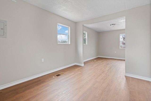 empty room with a textured ceiling and light wood-type flooring