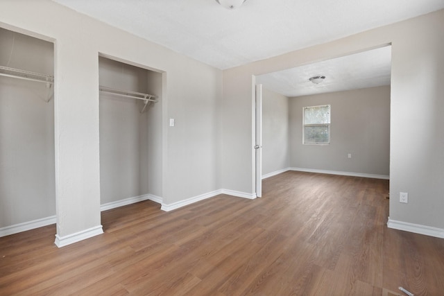 unfurnished bedroom featuring multiple closets and hardwood / wood-style flooring