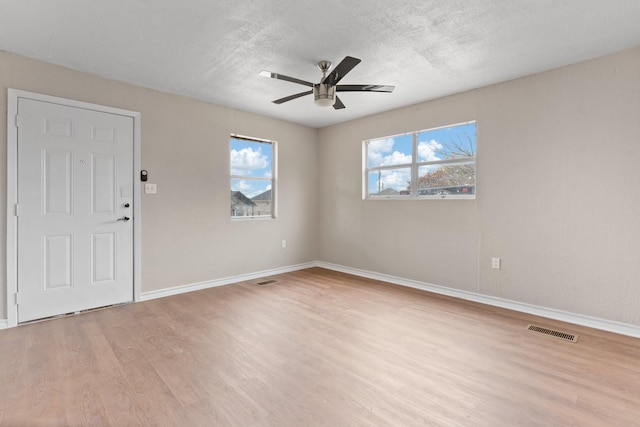 empty room with ceiling fan, a textured ceiling, and light wood-type flooring