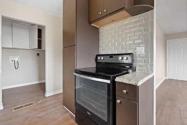 kitchen featuring black / electric stove, dark brown cabinetry, decorative backsplash, and light hardwood / wood-style flooring