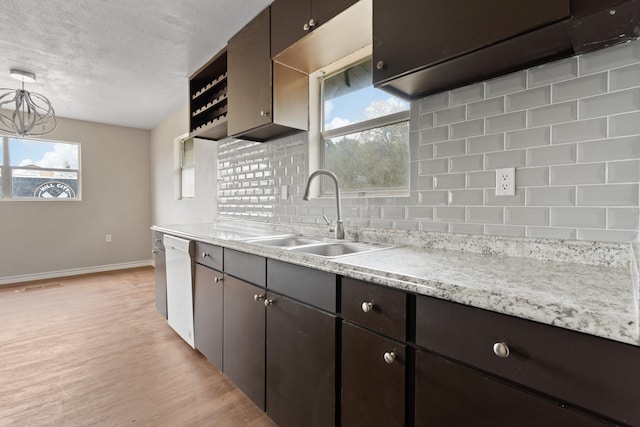 kitchen with sink, hanging light fixtures, white dishwasher, light hardwood / wood-style floors, and decorative backsplash