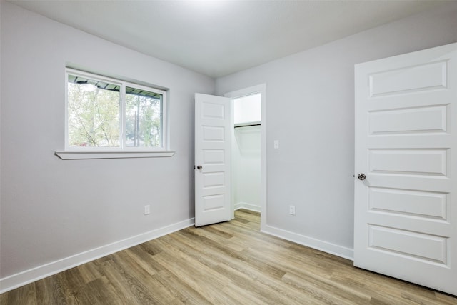 unfurnished bedroom with a spacious closet, light hardwood / wood-style floors, and a closet