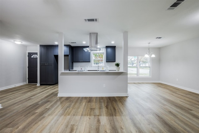 kitchen with island exhaust hood, a chandelier, and wood-type flooring