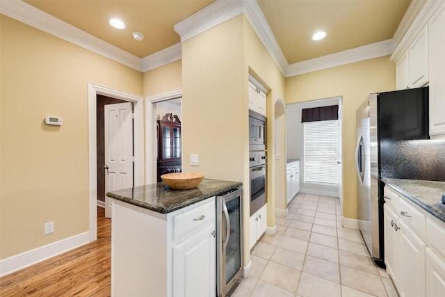 kitchen with white cabinetry, crown molding, beverage cooler, and dark stone counters