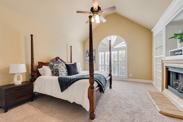 bedroom with ceiling fan, light colored carpet, a tiled fireplace, and vaulted ceiling