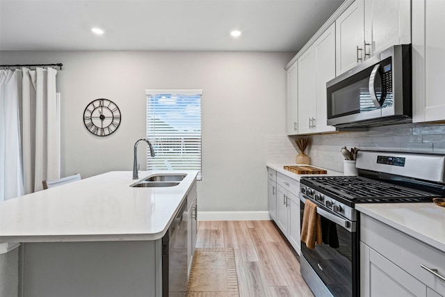 kitchen with sink, light hardwood / wood-style flooring, a center island with sink, and appliances with stainless steel finishes