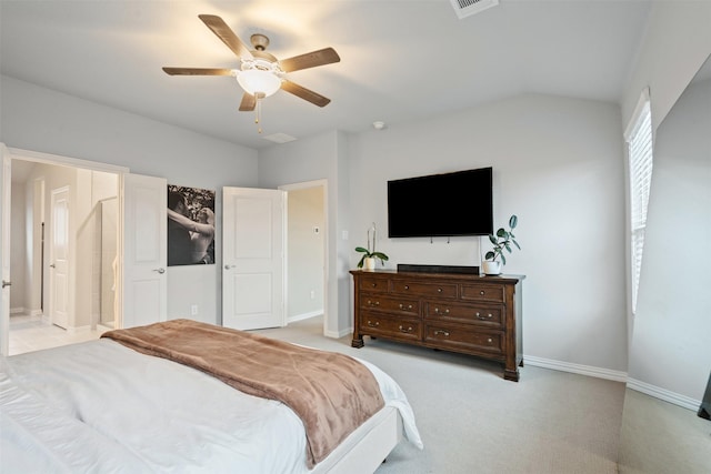 bedroom featuring ceiling fan, ensuite bathroom, light colored carpet, and vaulted ceiling