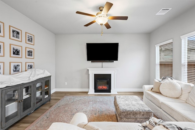 living room featuring ceiling fan and dark wood-type flooring