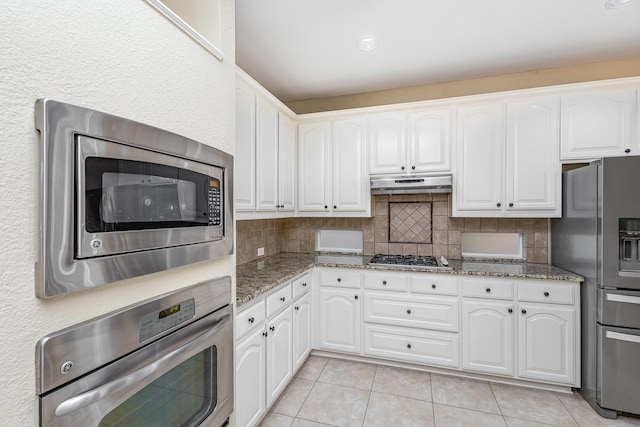 kitchen with decorative backsplash, white cabinets, and stainless steel appliances